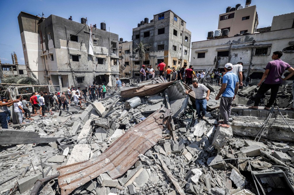 Palestinians inspect the ruins of a collapsed building destroyed by an Israeli air strike in Gaza City, on August 6, 2022. - Israel on August 6 hit Gaza with air strikes and the Palestinian Islamic Jihad militant group retaliated with a barrage of rocket fire, in the territory's worst escalation of violence since a war last year. Israel has said it was forced to launch a