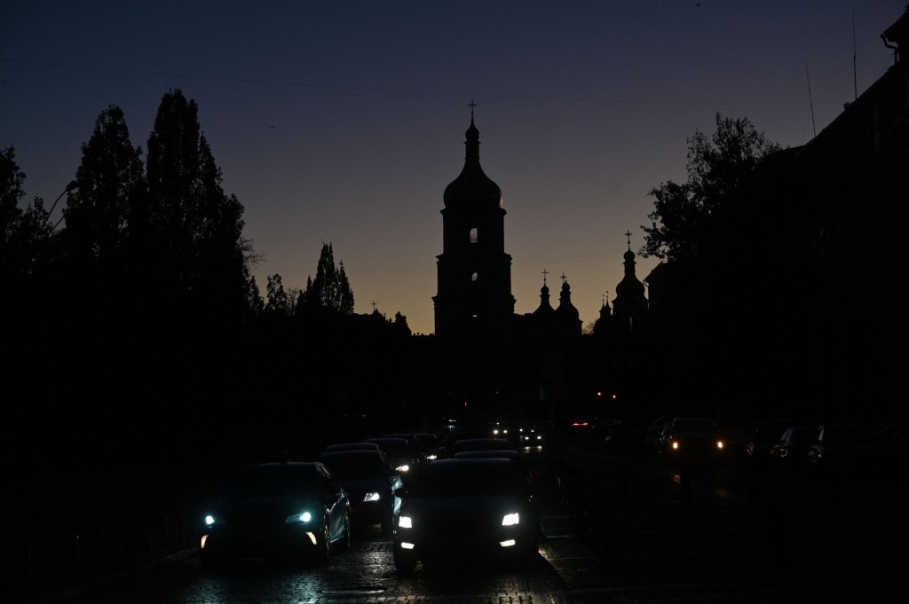 TOPSHOT - Vehicles drive along a street with the St. Sophia Cathedral silhouetted in the background, as the city is plunged into near darkness following a military strike that partially brought down the power infrastructure, in Kyiv on October 31, 2022. - Ukraine suffered sweeping blackouts and water supplies were cut for 80 percent of Kyiv residents on October 31, 2022, after another wave of Russian missile strikes on key infrastructure. The Ukrainian army said