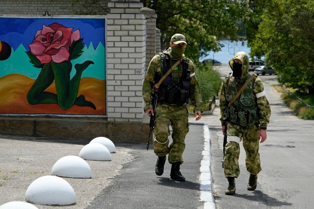 FILE - Two Russian soldiers patrol an administrative area at the Khersonvodokanal (water channel) in Kherson, Kherson region, south Ukraine, on May 20, 2022. In the southern city of Kherson, one of the first seized by Russia and a key target of an unfolding Ukrainian counteroffensive, the Ukrainian mayor tried to stand his ground. As Russians seized parts of eastern and southern Ukraine in the 8-month-old war, mayors, civilian administrators and others, including nuclear power plant workers, say they have been abducted, threatened or beaten to force their cooperation. (AP Photo, File)