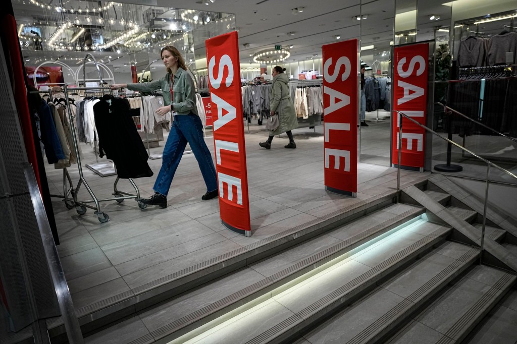 An employee pushes a rail of clothes in the Moscow store for the last time today