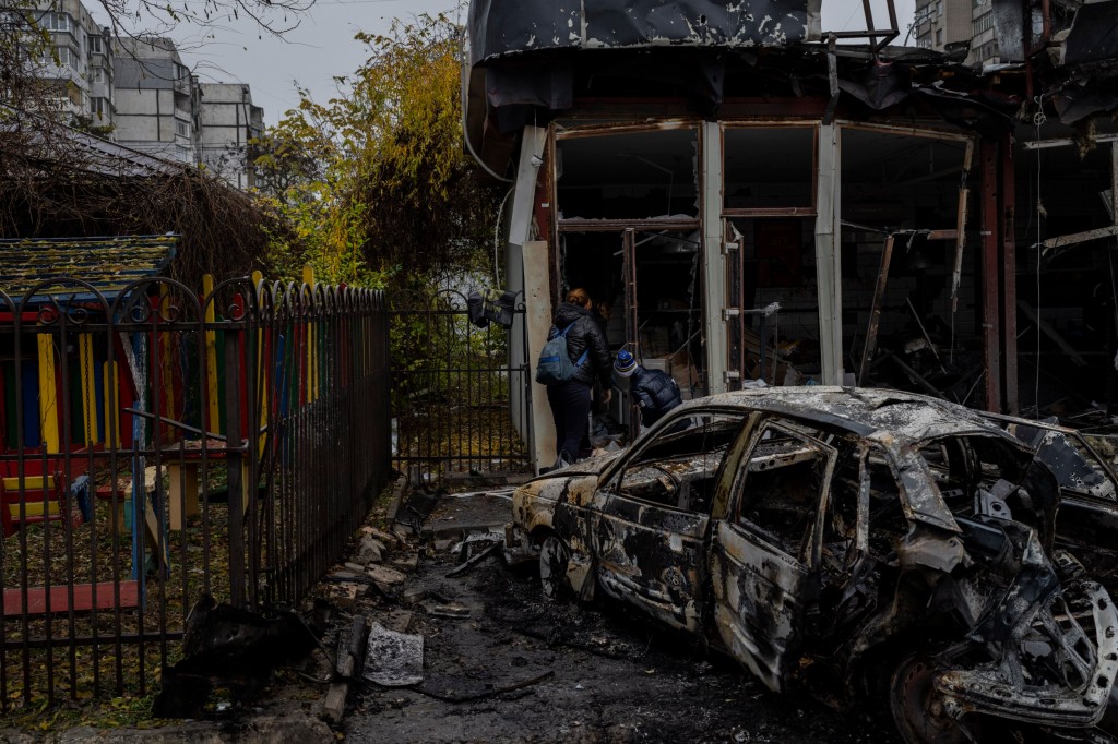 Residents check the damage of a shop destroyed a day earlier during a Russian attack in Kherson, southern Ukraine, Friday, Nov. 25, 2022. A barrage of missiles struck the recently liberated city of Kherson for the second day Friday in a marked escalation of attacks since Russia withdrew from the city two weeks ago following an eight-month occupation. (AP Photo/Bernat Armangue)