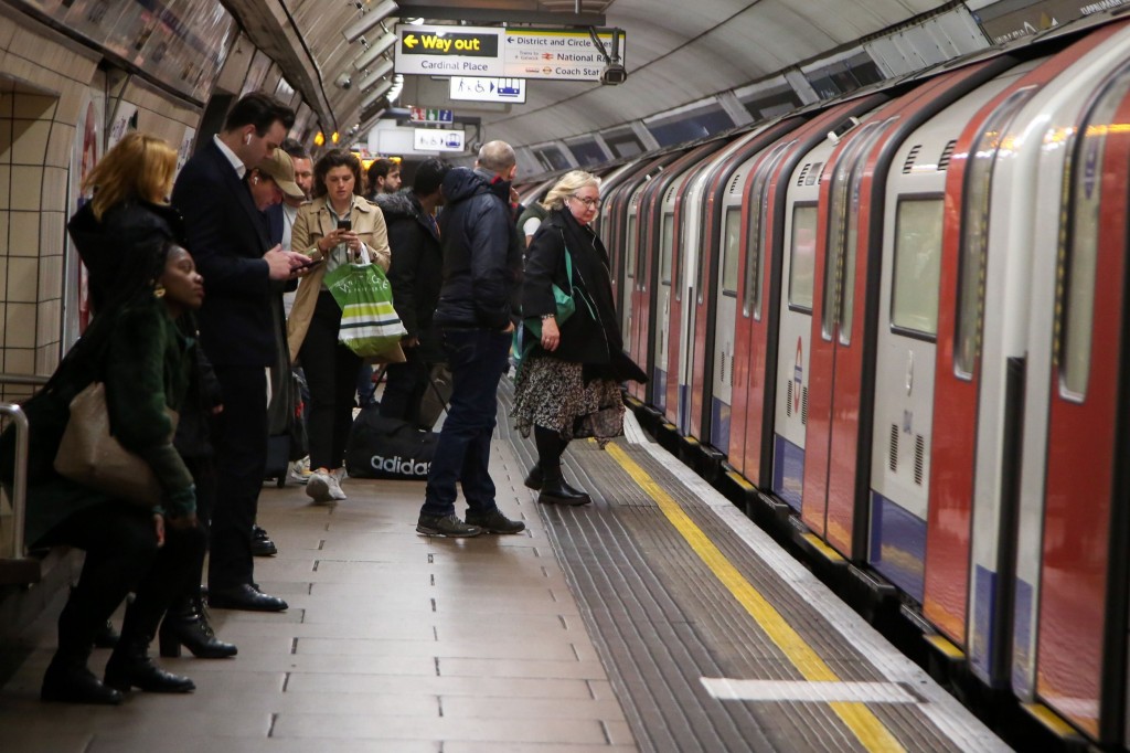 Commuters wait for a train at a London underground station