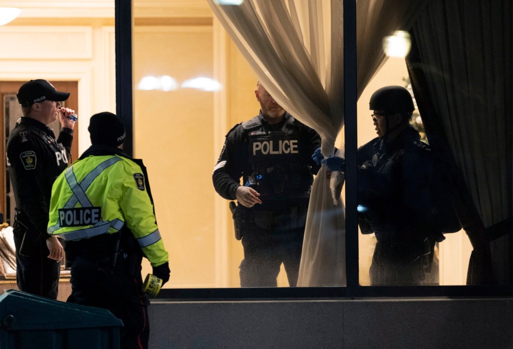 Police stand in the lobby of a condominium building following a shooting in Vaughan, Ontario, Sunday, Dec. 18, 2022. Authorities said multiple people were shot and killed in a unit of the building in the Toronto suburb and the gunman was killed by police. (Arlyn McAdorey/The Canadian Press via AP)