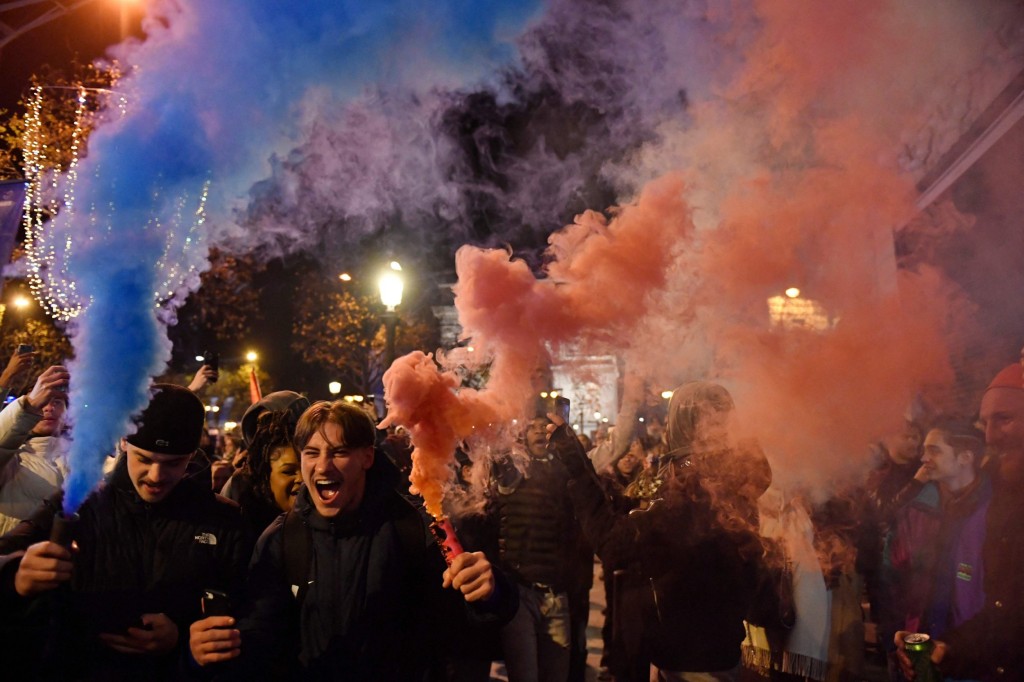 Fans hold smoke flares as they celebrate France's victory over Morocco in the Qatar 2022 World Cup semi-final on the Champs-Elysees in Paris on December 14