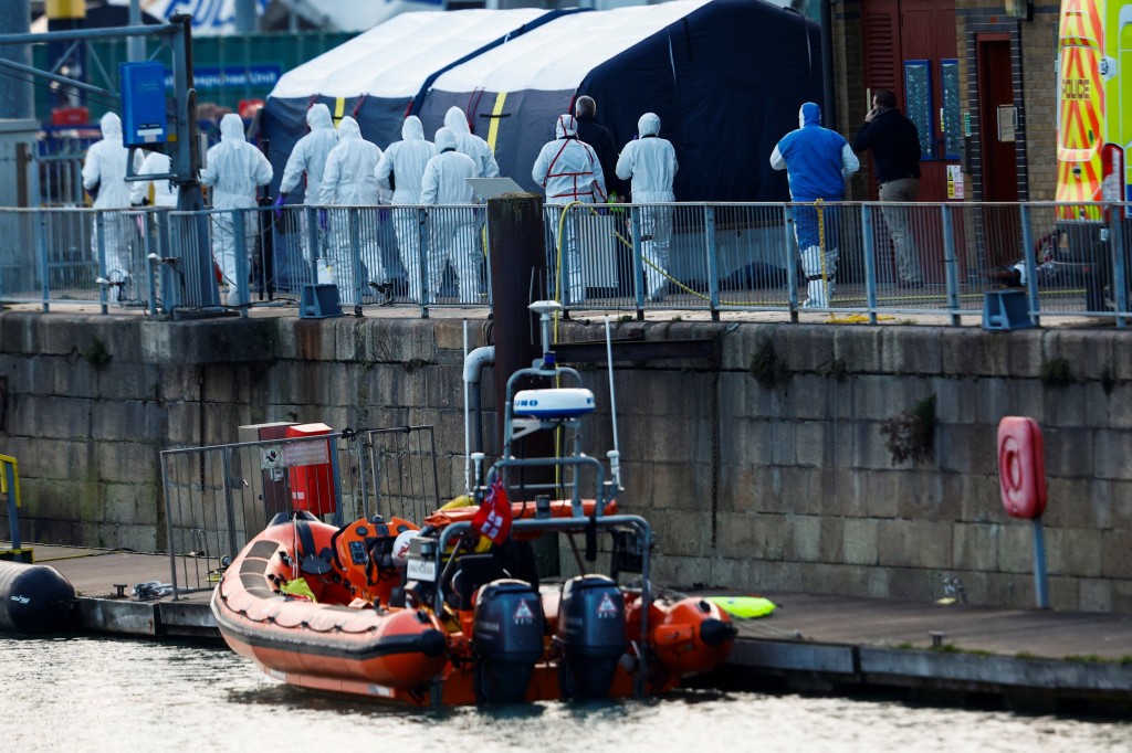 Police forensics officers wearing protective gear walk at the Port of Dover after a small boat loaded with migrants capsized in the English Channel, in Dover, Britain December 14, 2022. REUTERS/Peter Nicholls