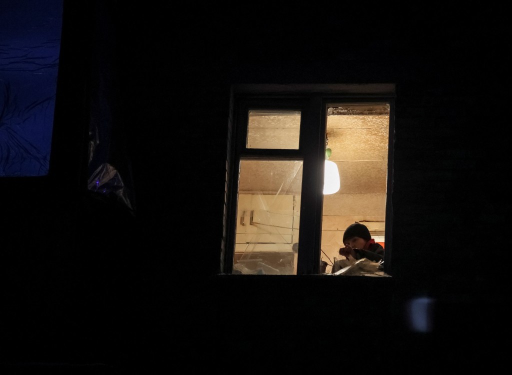 A local resident removes shards of glass from his broken window in a flat at a residential building damaged by a Russian drone attack, as their attack on Ukraine continues, in Kyiv, Ukraine December 14, 2022. REUTERS/Gleb Garanich