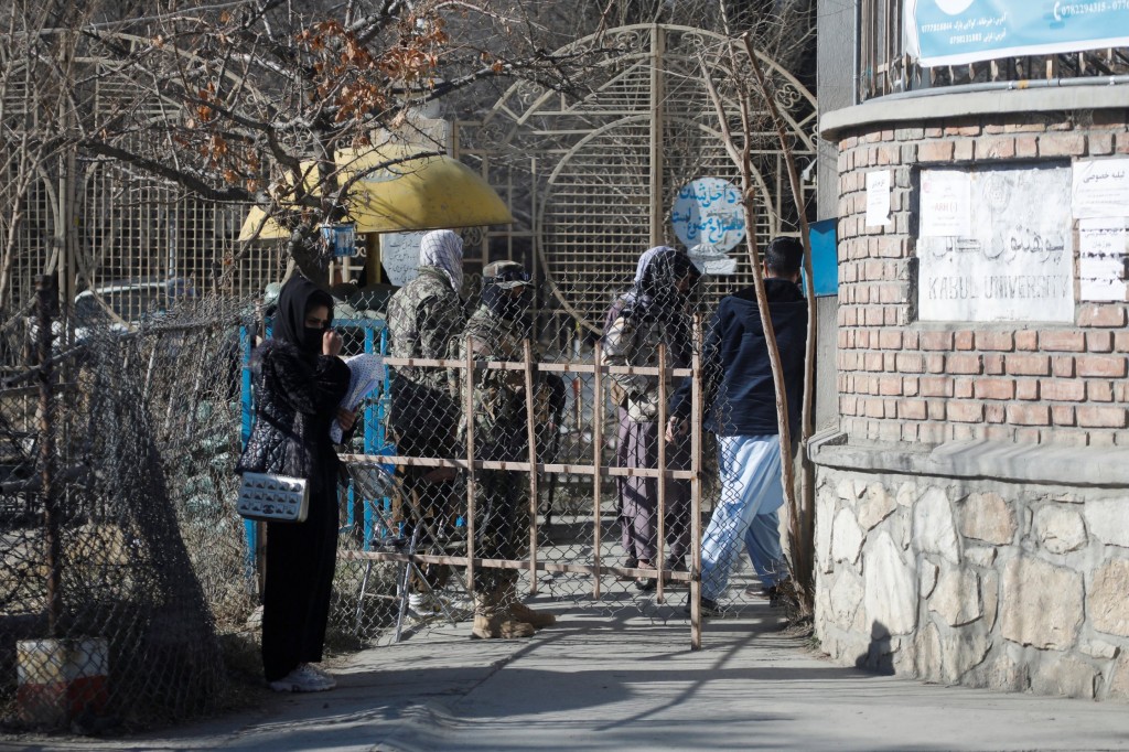 An Afghan female student stands in front of the entrance gate of Kabul University in Kabul.