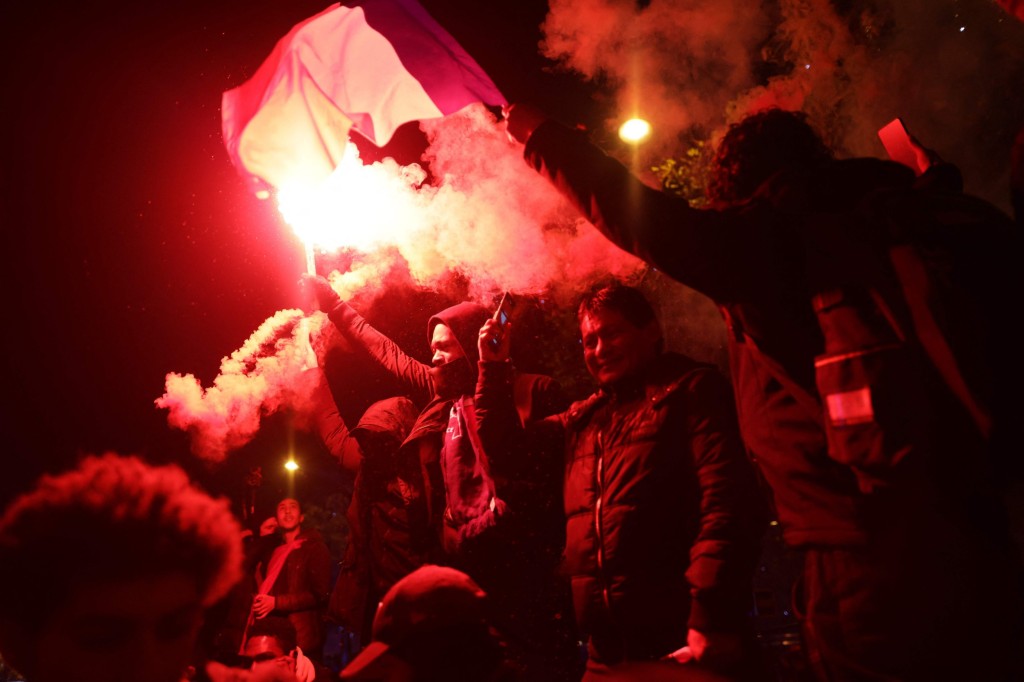 A football fans holds a smoke flare after France's victory over Morocco in the Qatar 2022 World Cup semi-final, on the Champs-Elysees in Paris on December 14, 2022. (Photo by Thibaud MORITZ / AFP) (Photo by THIBAUD MORITZ/AFP via Getty Images)