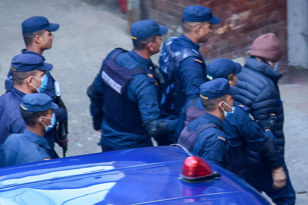 Policemen escort Charles Sobhraj (R) to the immigration office in Kathmandu on December 23, 2022. - French serial killer Charles Sobhraj, responsible for multiple murders of young foreigners in the 1970s across Asia, was set to be released from prison on December 23, jail authorities and his lawyer said. Sobhraj, 78, whose life was chronicled in the successful Netflix/BBC series