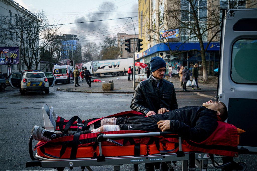 TOPSHOT - A man helps an injured civilian after Russian shelling to Ukrainian city of Kherson on December 24, 2022, where five were killed and 20 injured. - Ukrainian President Volodymyr Zelensky on December 24, 2022 blasted Russian