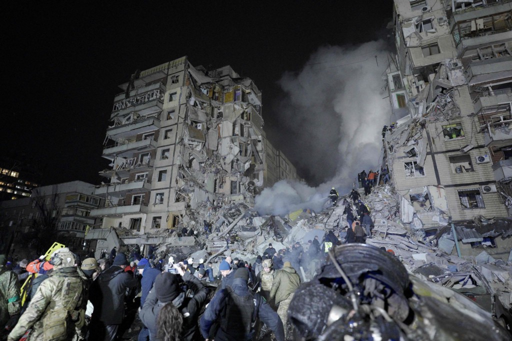 Rescuers works on a residential building destroyed after a missile strike, in Dnipro on January 14, 2023. - A strike on a residential building in the eastern Ukrainian city of Dnipro on January 14, 2023 killed at least five people and wounded 39, officials said, as the president blasted Russian