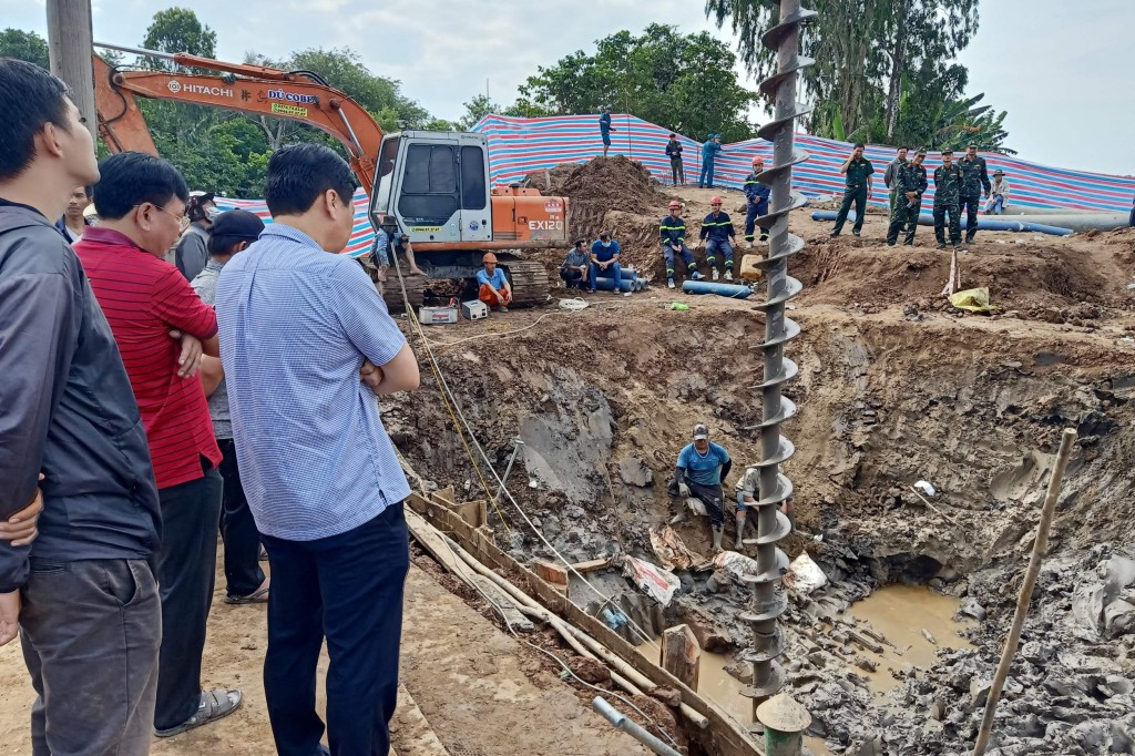 Rescuers look down into the site of where a 10-year-old boy is thought to be trapped in a 35-metre deep shaft at a bridge construction area in Vietnam's Dong Thap province on January 2, 2023. - Hundreds of rescuers in Vietnam battled January 2 to free a 10-year-old boy who fell into a 35-metre deep hole on a construction site two days ago. (Photo by AFP) (Photo by STR/AFP via Getty Images)