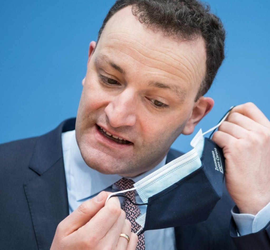 German Health Minister Jens Spahn adjusts his face mask.