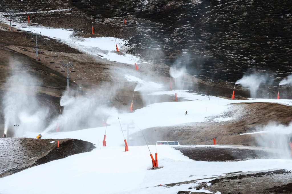 A staff member works on a slope as snow cannons operate due to lack of snow at the Peyragudes ski resort, southwestern France on January 5, 2023. (Photo by Charly TRIBALLEAU / AFP) (Photo by CHARLY TRIBALLEAU/AFP via Getty Images)