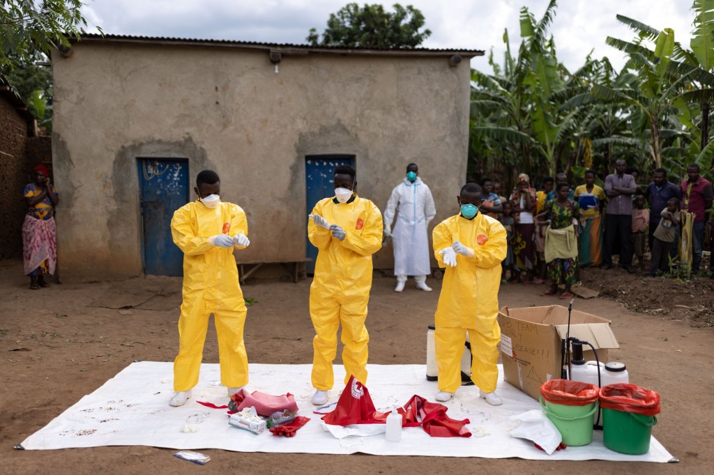 MUBENDE, UGANDA - OCTOBER 13: Red Cross workers don PPE prior to burying a 3-year-old boy suspected of dying from Ebola on October 13, 2022 in Mubende, Uganda. Emergency response teams, isolation centres and treatment tents have been set up by the Ugandan health authorities around the central Mubende district after 17 recorded deaths and 48 confirmed cases from an outbreak of the Ebola virus. The first death from this outbreak of the Ebola-Sudan strain of the virus was announced on 19 September and as yet, there is no vaccine for this strain. (Photo by Luke Dray/Getty Images)