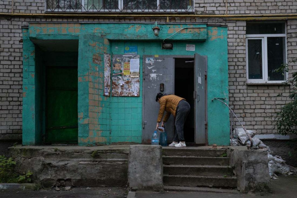 Snapshot - Ukraine 1 year on Svitlana fetches drinkable water from a tap in her Mykolaiv neighborhood and carries it back to her home. The city has been without drinking water for months.