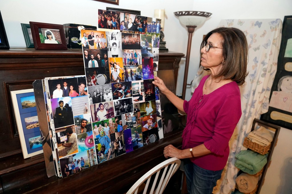 Dolores Cruz looks at a college of pictures of her youngest son, Eric Cruz, and some of his bandmates on Wednesday, Feb. 1, 2023, at her home in San Gabriel, Calif. Cruz published an essay in 2022 about grieving for her son, who died in a car crash in 2017.