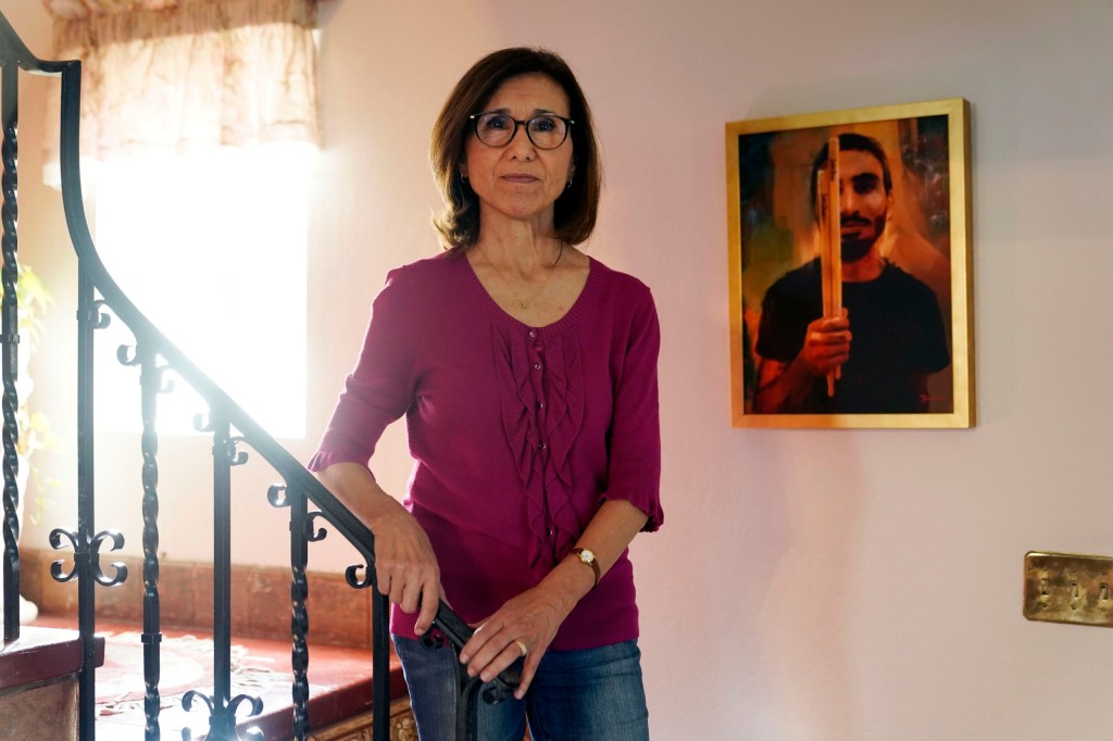 Dolores Cruz poses next to a painting of her youngest son, Eric Cruz, on Wednesday, Feb. 1, 2023, at her home in San Gabriel, Calif. Cruz published an essay in 2022 about grieving for her son, who died in a car crash in 2017.