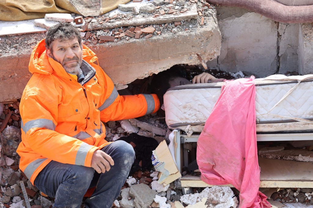 Mesut Hancer holds the hand of his 15-year-old daughter Irmak, who died in the earthquake in Kahramanmaras, close to the quake's epicentre, the day after a 7.8-magnitude earthquake struck the country's southeast, on February 7, 2023. - Rescuers in Turkey and Syria braved frigid weather, aftershocks and collapsing buildings, as they dug for survivors buried by an earthquake that killed more than 5,000 people. Some of the heaviest devastation occurred near the quake's epicentre between Kahramanmaras and Gaziantep, a city of two million where entire blocks now lie in ruins under gathering snow. (Photo by Adem ALTAN / AFP) (Photo by ADEM ALTAN/AFP via Getty Images)