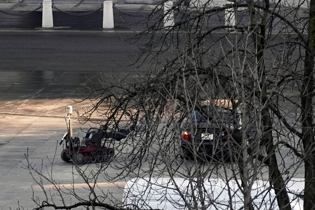 A police robot stands next to a suspicious car in front of the Swiss Parliament, the Bundeshaus in Bern, during the large-scale operation of the Bern police, where several buildings were evacuated and the Bundesplatz and some streets around were widely cordoned off, on Tuesday, Feb. 14, 2023. A man wearing a bulletproof vest and weapon holster, who allegedly parked the car in the middle of the Bundesplatz near one of its entrances, was found to explosives and arrested. (Manuel Lopez/Keystone via AP)