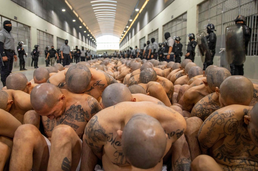 Handout picture released by the Press Secretary of the Presidency of El Salvador showing police officers in riot gear guarding the arrival of inmates belonging to the MS-13 and 18 gangs to the new prison