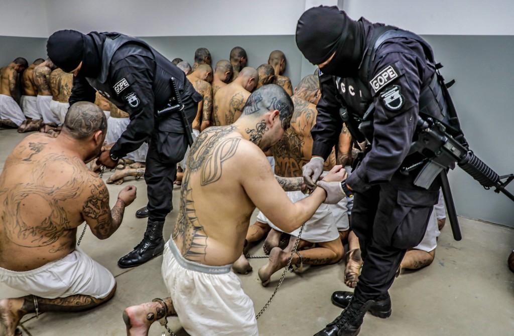 Handout picture released by the Press Secretary of the Presidency of El Salvador showing police officers in riot gear guarding the arrival of inmates belonging to the MS-13 and 18 gangs to the new prison