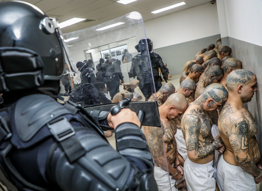 Handout picture released by the Press Secretary of the Presidency of El Salvador showing police officers in riot gear guarding the arrival of inmates belonging to the MS-13 and 18 gangs to the new prison